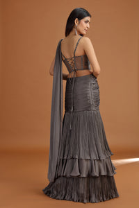 Woman wearing a dark grey lehenga set with a matching dupatta on an orange background
