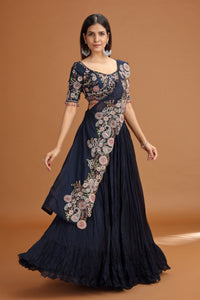 Woman wearing a dark blue lehenga with floral patterns on a brown background