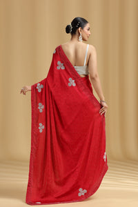 Woman wearing a red satin silk saree with silver floral patterns on a beige background