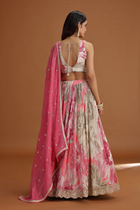 Woman wearing a pink and floral lehenga with a brown background
