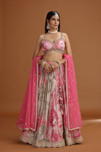 Woman wearing a traditional pink  lehenga with jewelry against an orange background