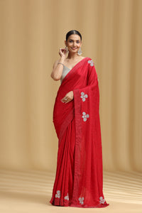 Woman wearing a red saree with silver floral patterns on a beige background