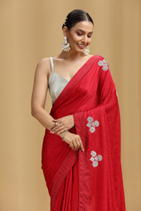 Woman wearing a red saree with silver floral patterns on a beige background