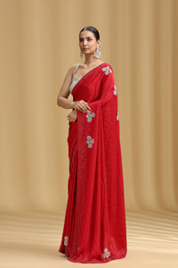 Woman wearing a red saree with white floral patterns on a beige background