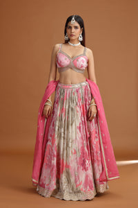 Woman wearing a pink floral design lehenga on a brown background