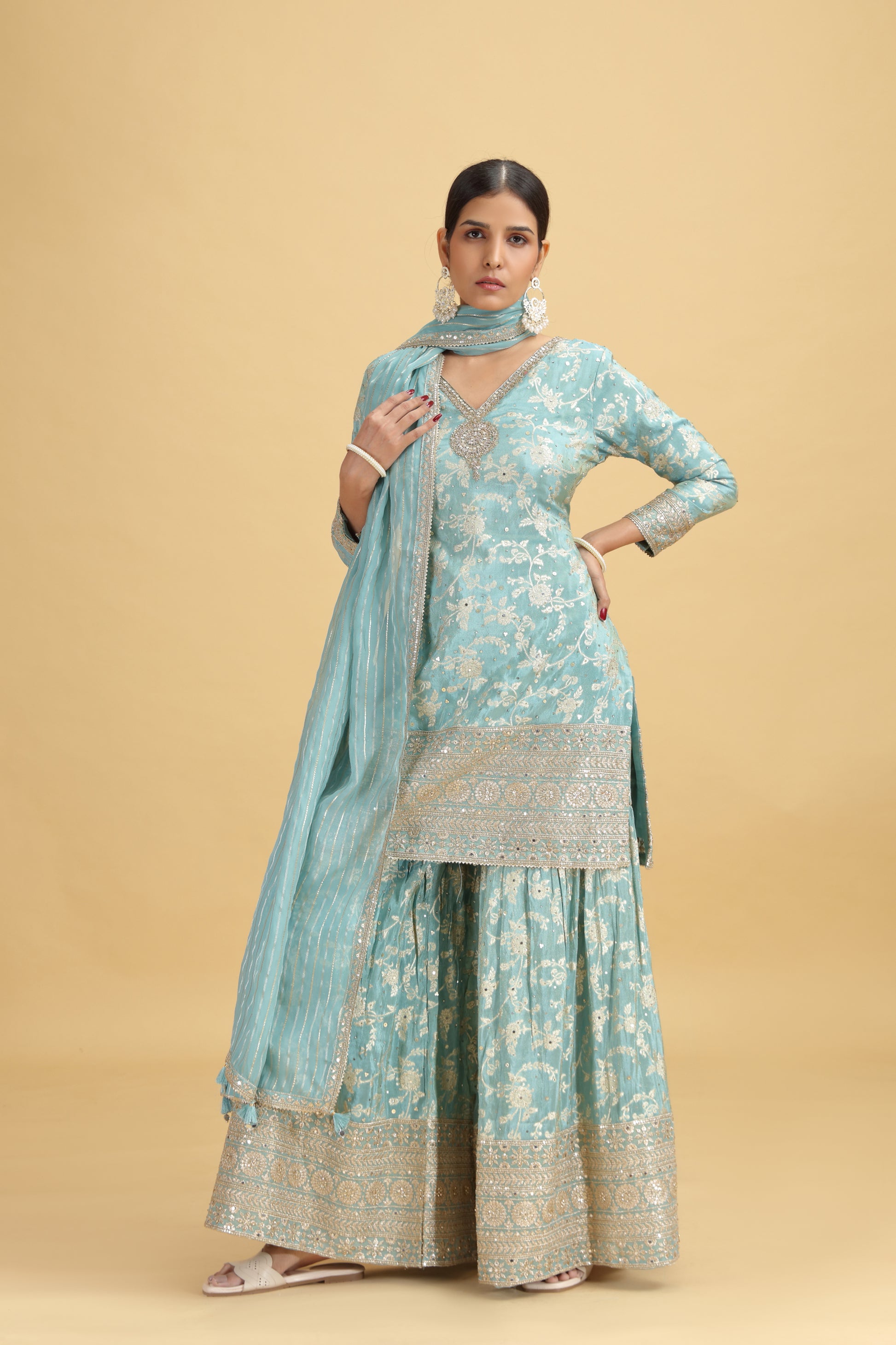 Woman wearing a light blue traditional outfit with a beige background