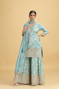 Woman wearing a light blue traditional outfit with a beige background
