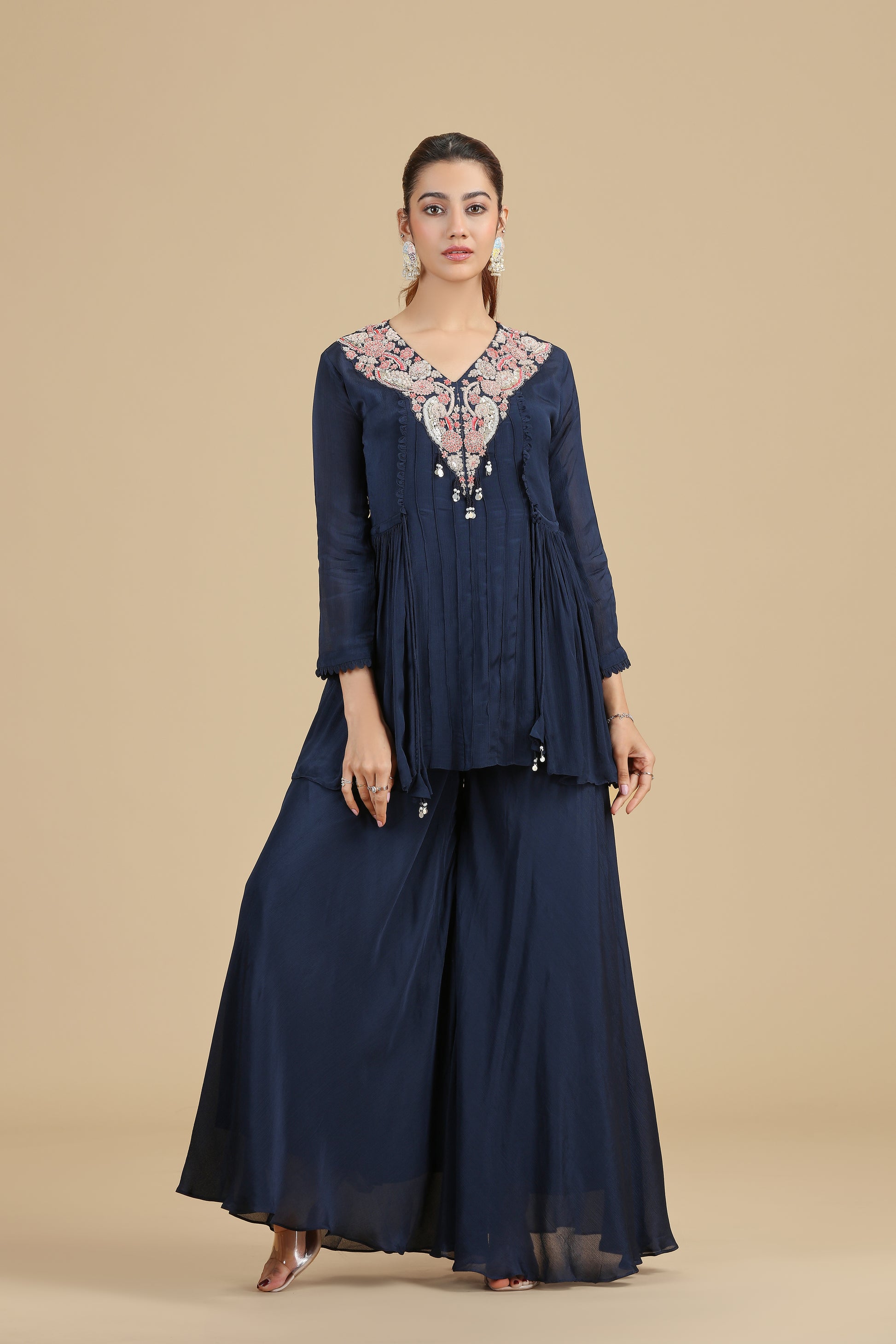 Woman wearing a navy blue outfit with floral embroidery on a beige background
