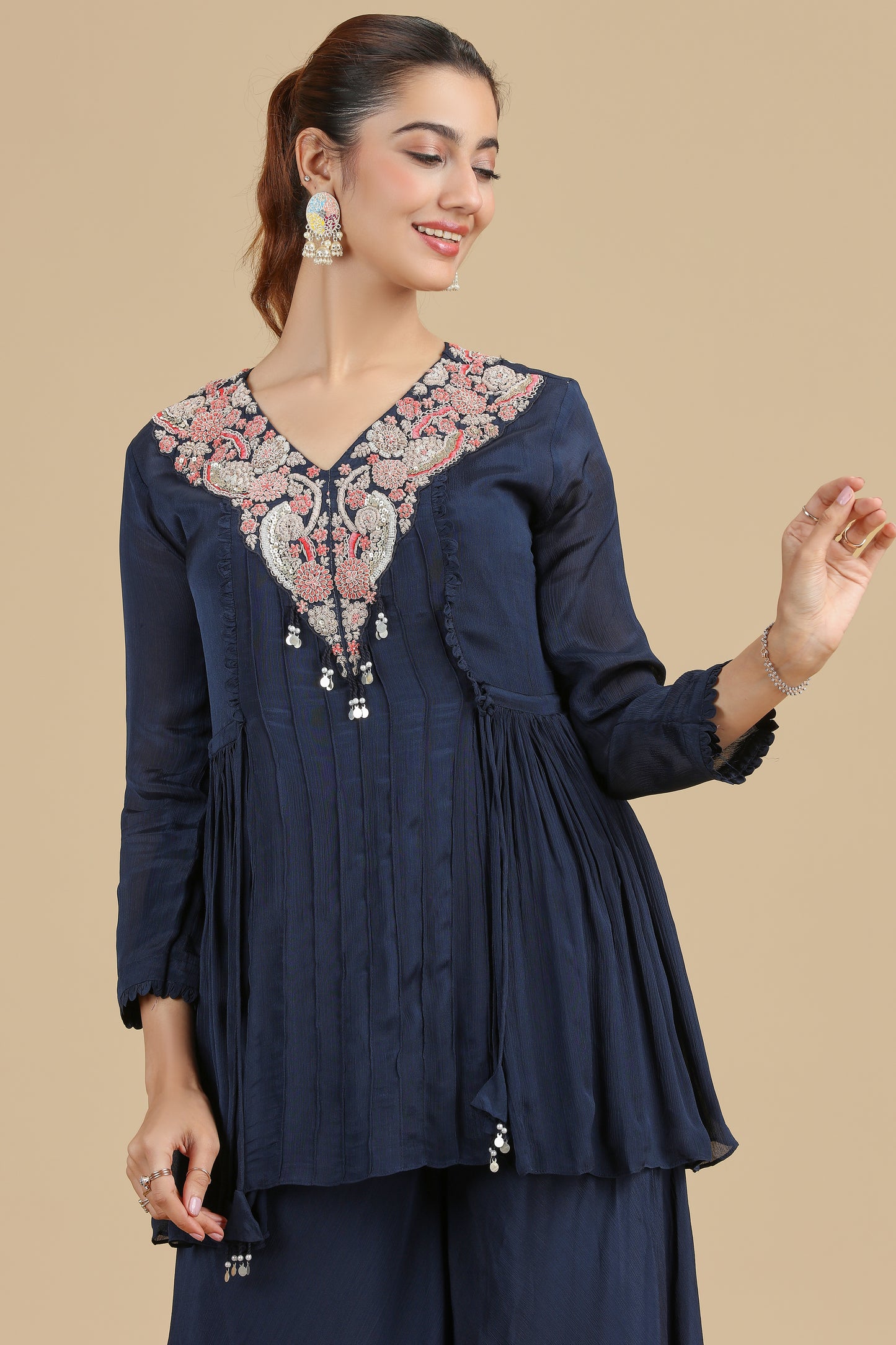 Woman wearing a navy blue embroidered kurta set on a beige background