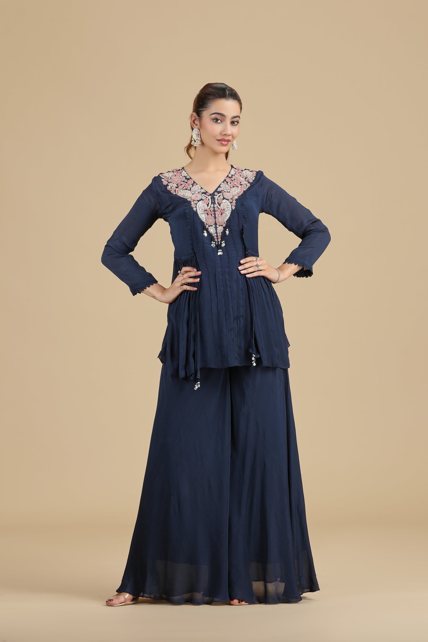 Woman wearing a navy blue traditional kurta with intricate designs on a beige background