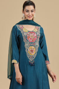 Woman wearing a teal embroidered kurta set with a beige background
