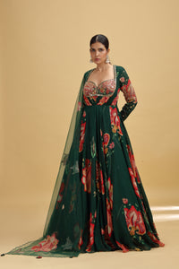 Woman wearing a dark green floral gown with a matching blouse on a beige background