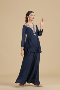 Woman wearing a navy blue Chinnon Kurta Set with floral embroidery on a beige background