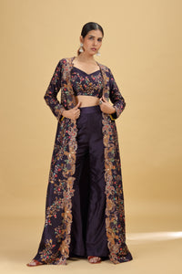 Woman wearing a floral kimono-style jacket over a dark purple suit on a beige background