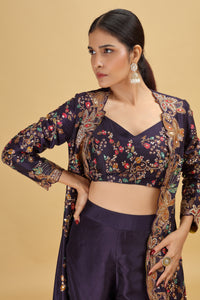 Woman wearing a dark purple floral blouse with matching pants against a beige background