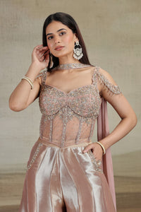 Woman wearing a peach net organza salwar suit with intricate designs and jewelry against a neutral background