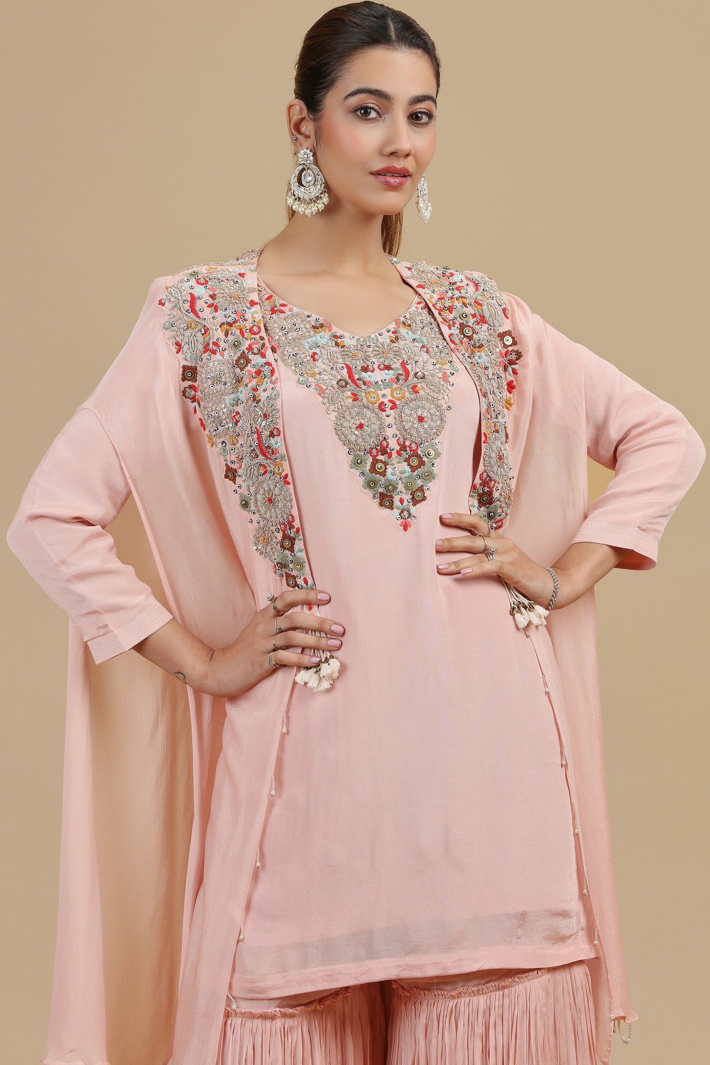 Woman wearing a pink traditional outfit with floral embroidery on a beige background