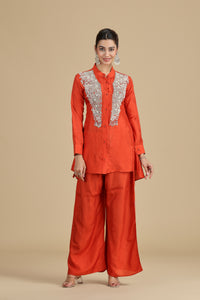 Woman wearing an orange traditional outfit with lace details on a beige background