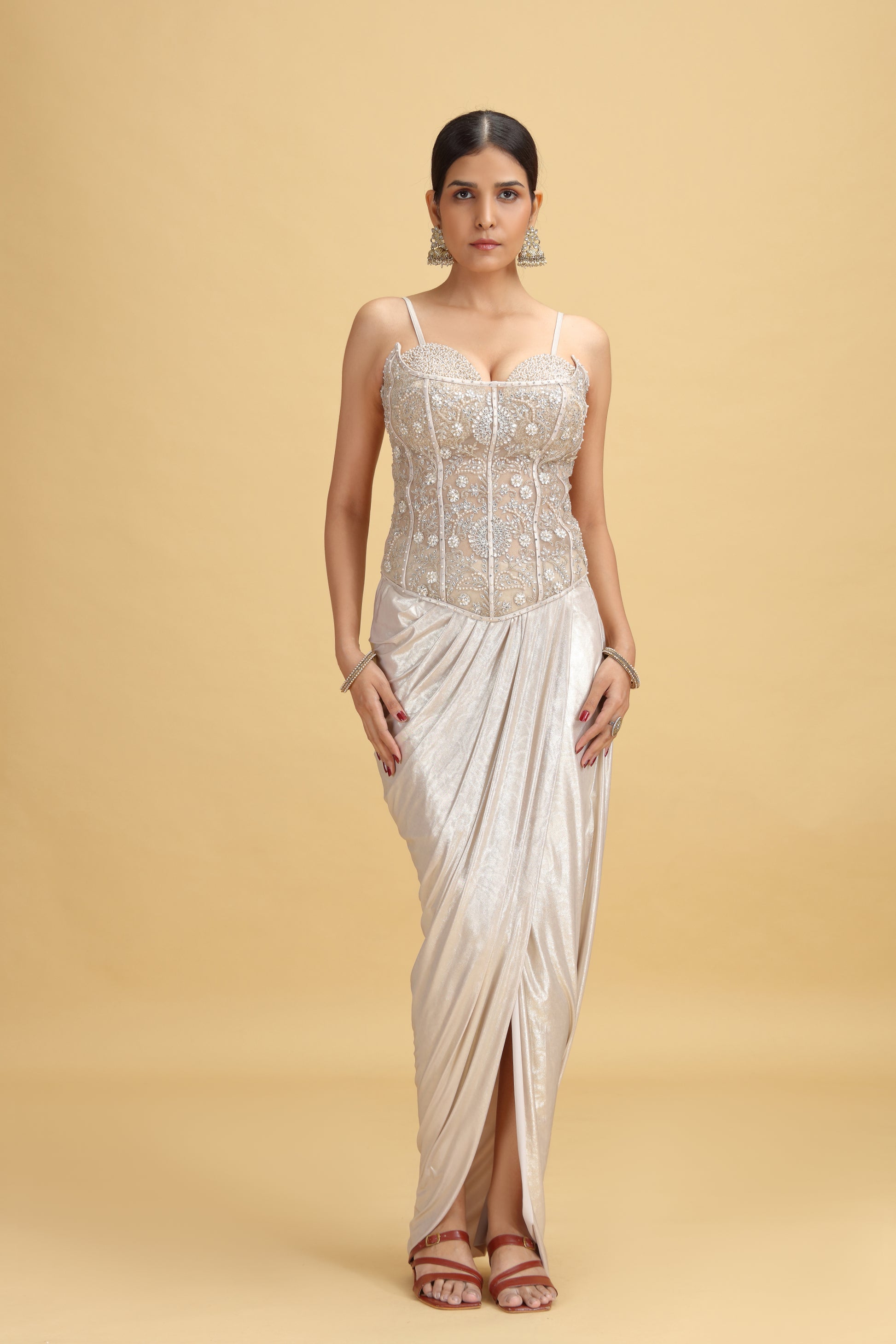 Woman wearing a white golden salwar suit set with a gold border on a beige background