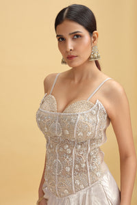 Woman wearing a beaded and embroidered outfit on a beige background