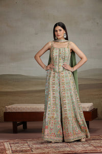 Woman wearing a green crepe salwar suit with a neutral background