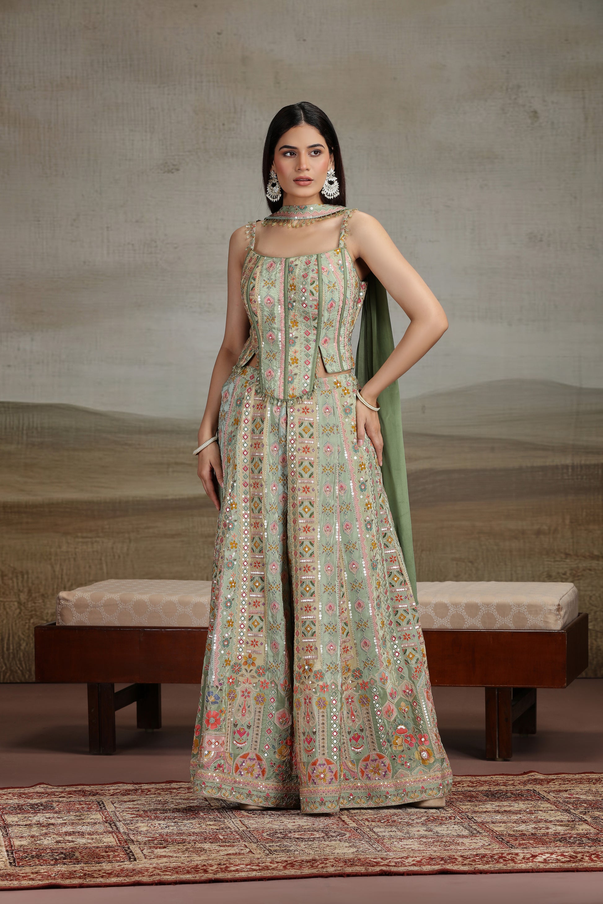 Woman in a floral dress standing in a room with a textured wall and bench.