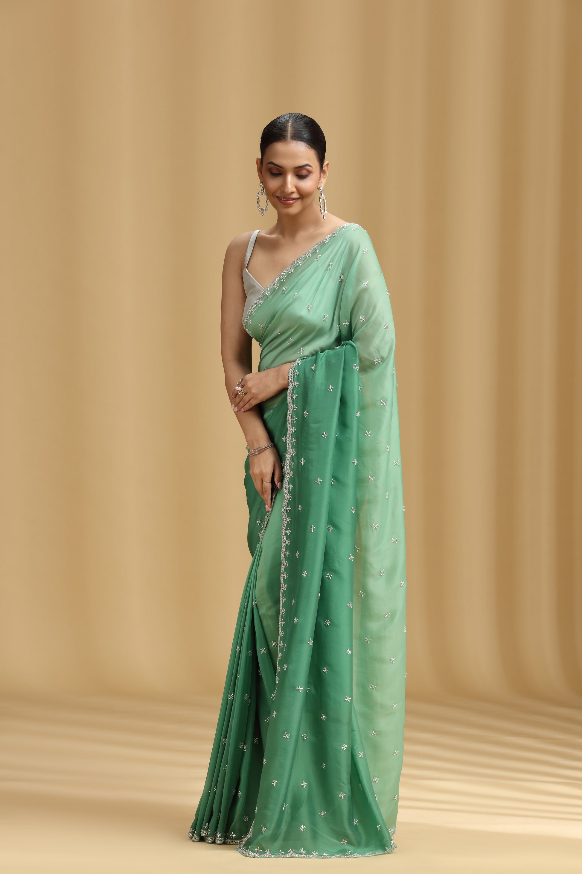 Woman wearing a green saree with a beige background
