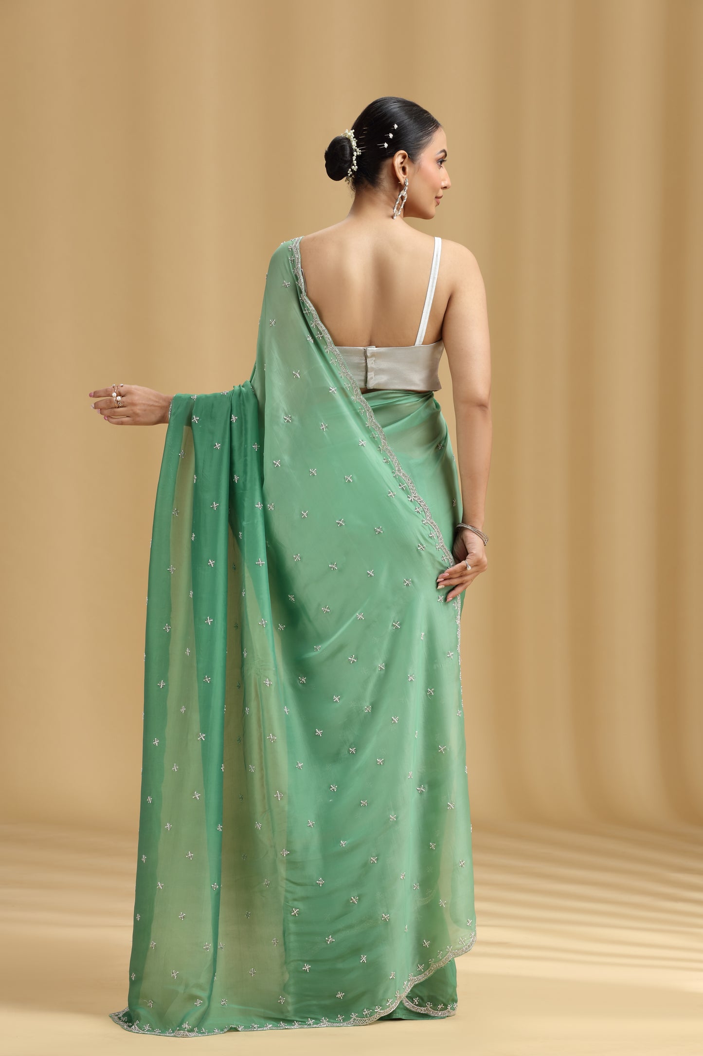 Woman wearing a green saree with a beige background