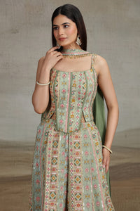 Woman wearing a patterned green dress with a neutral background