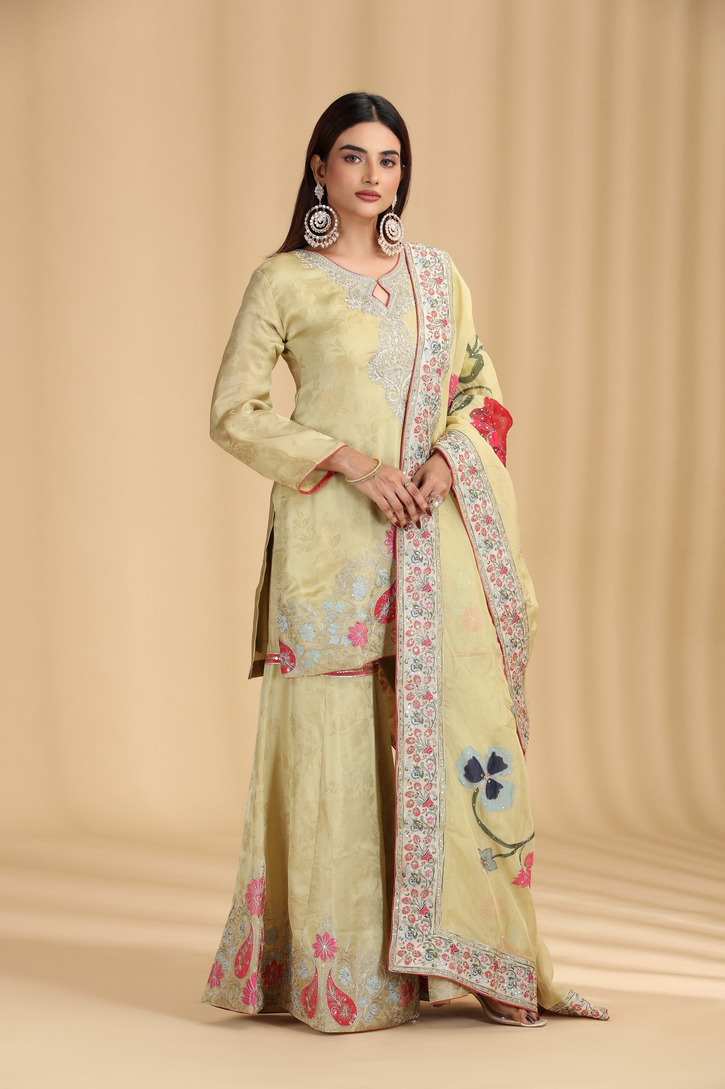 Woman wearing a light green traditional outfit with floral patterns on a beige background