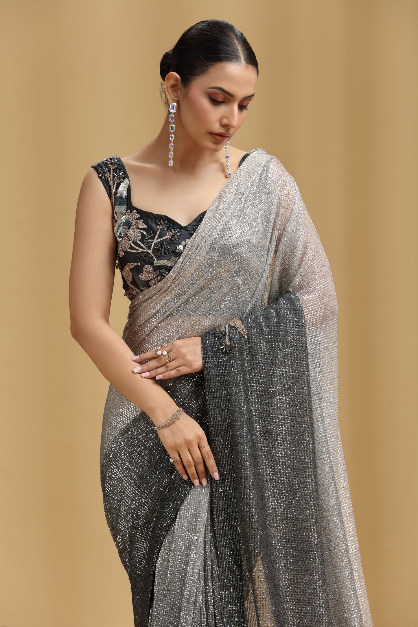 Woman wearing a silver saree with a black blouse against a beige background