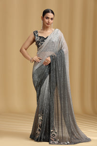 Woman wearing a black and gray saree with a beige background