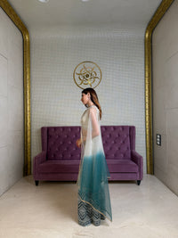 Woman standing in a room with a purple couch and decorative wall.