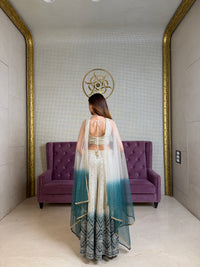 Woman standing in a room with a purple couch and decorative wall.