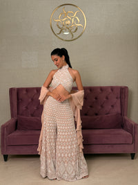 Woman in a patterned dress standing next to a purple couch with a decorative logo on the wall.