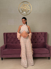 Woman wearing a long, patterned Pink Georgette Salwar Kameez in front of a purple couch.