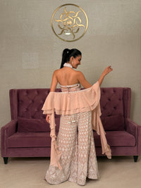 Woman in a beige dress standing next to a purple couch with a gold logo on the floor.