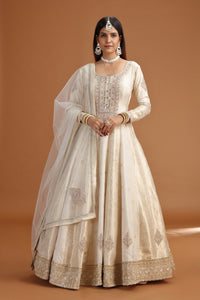 Woman wearing a traditional cream-colored outfit with a brown background