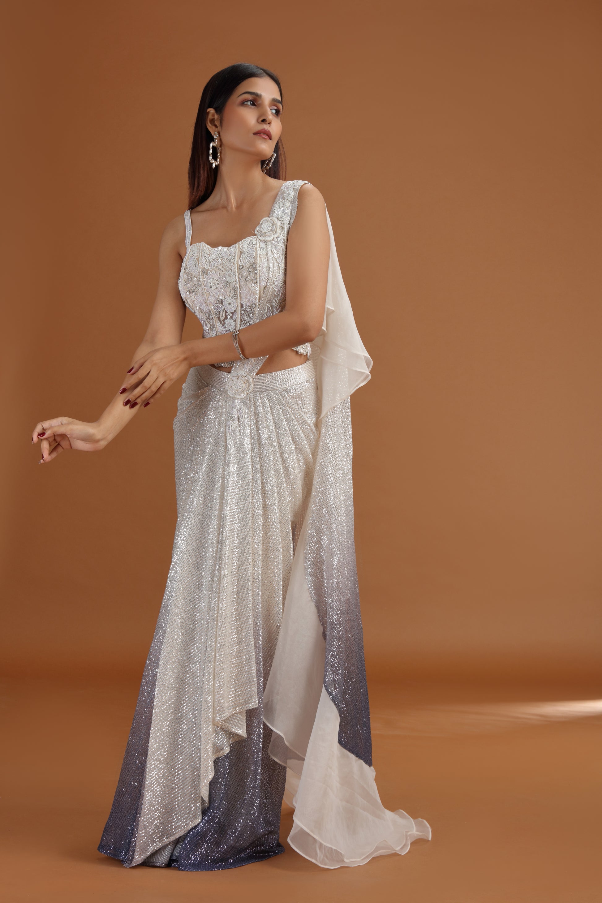 Woman wearing ivory net saree with a plain background