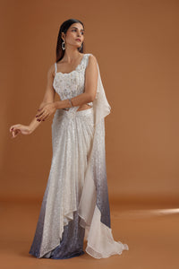 Woman wearing ivory net saree with a plain background