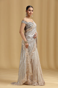Woman wearing a silver pure organza saree with a beige background