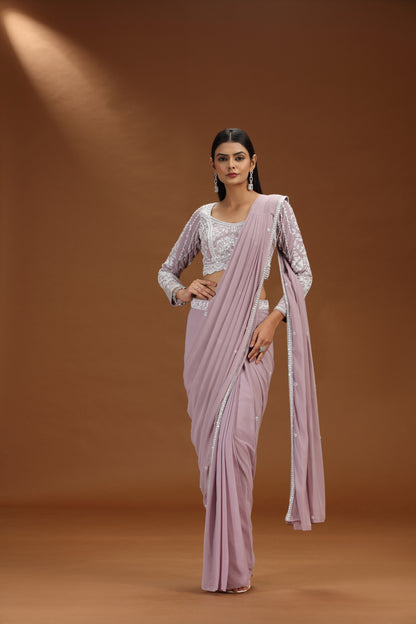 Woman wearing a light pink saree with a brown background