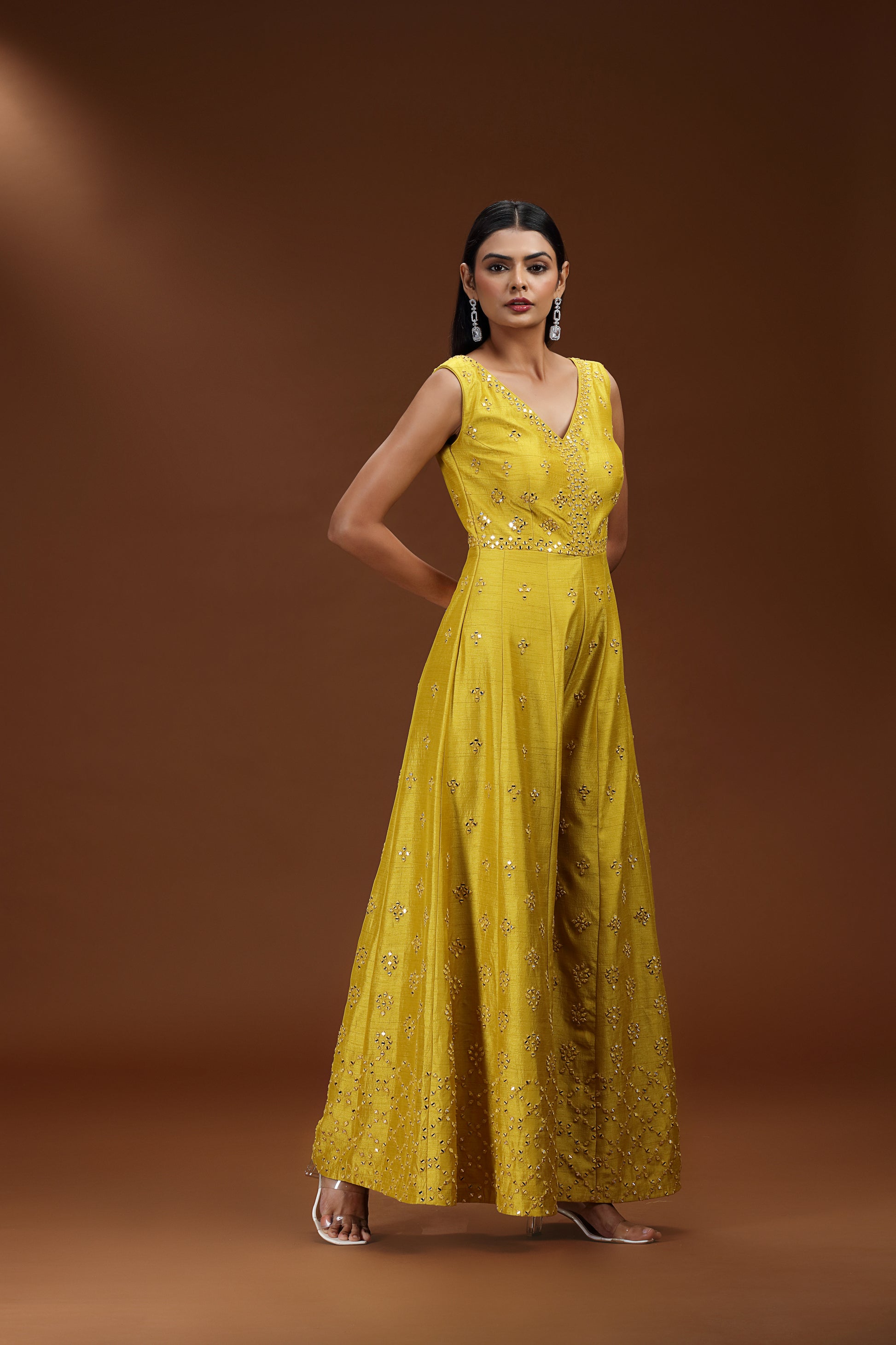 Woman wearing a yellow dress with intricate detailing on a brown background