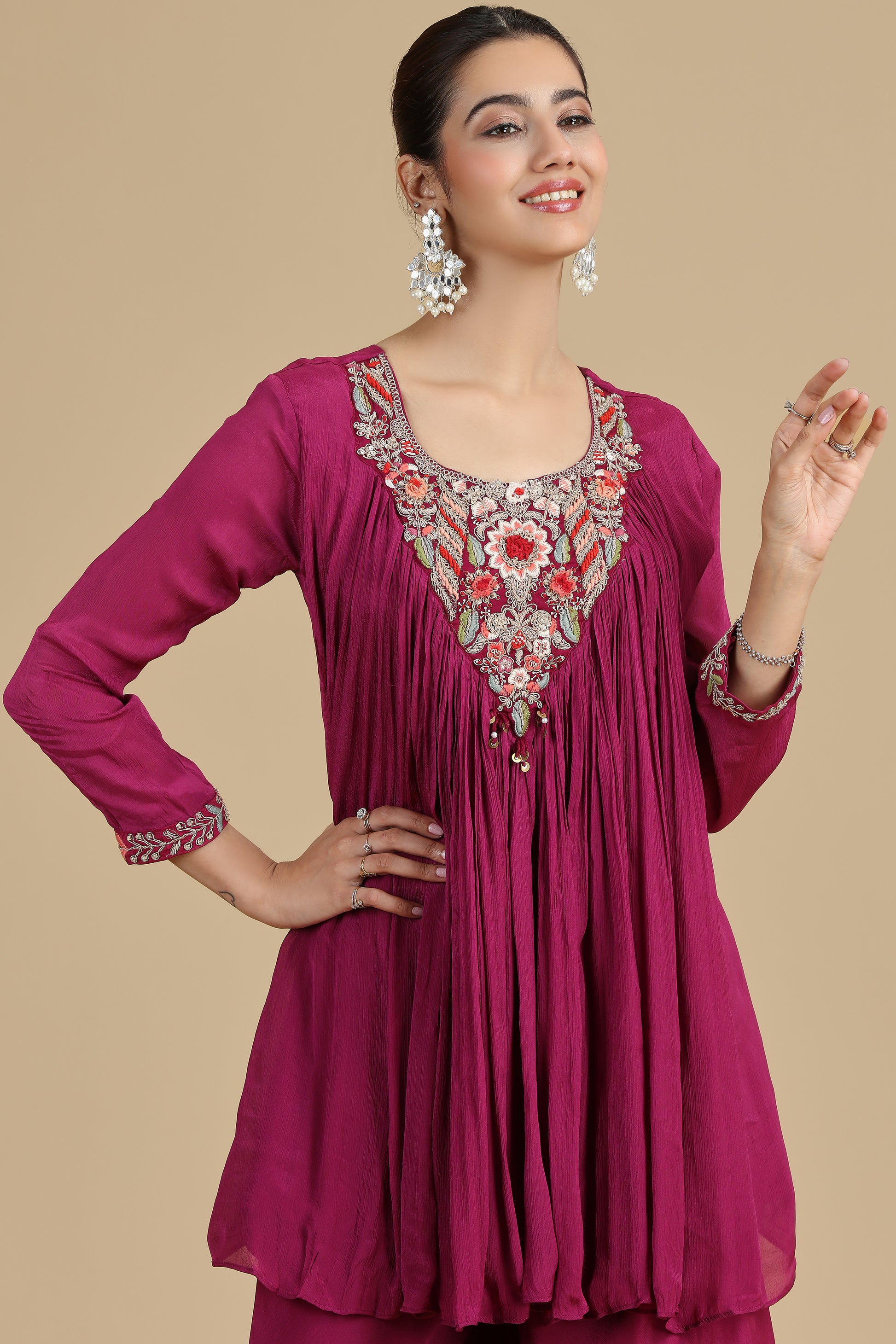 Woman wearing a magenta kurta with intricate embroidery on a beige background