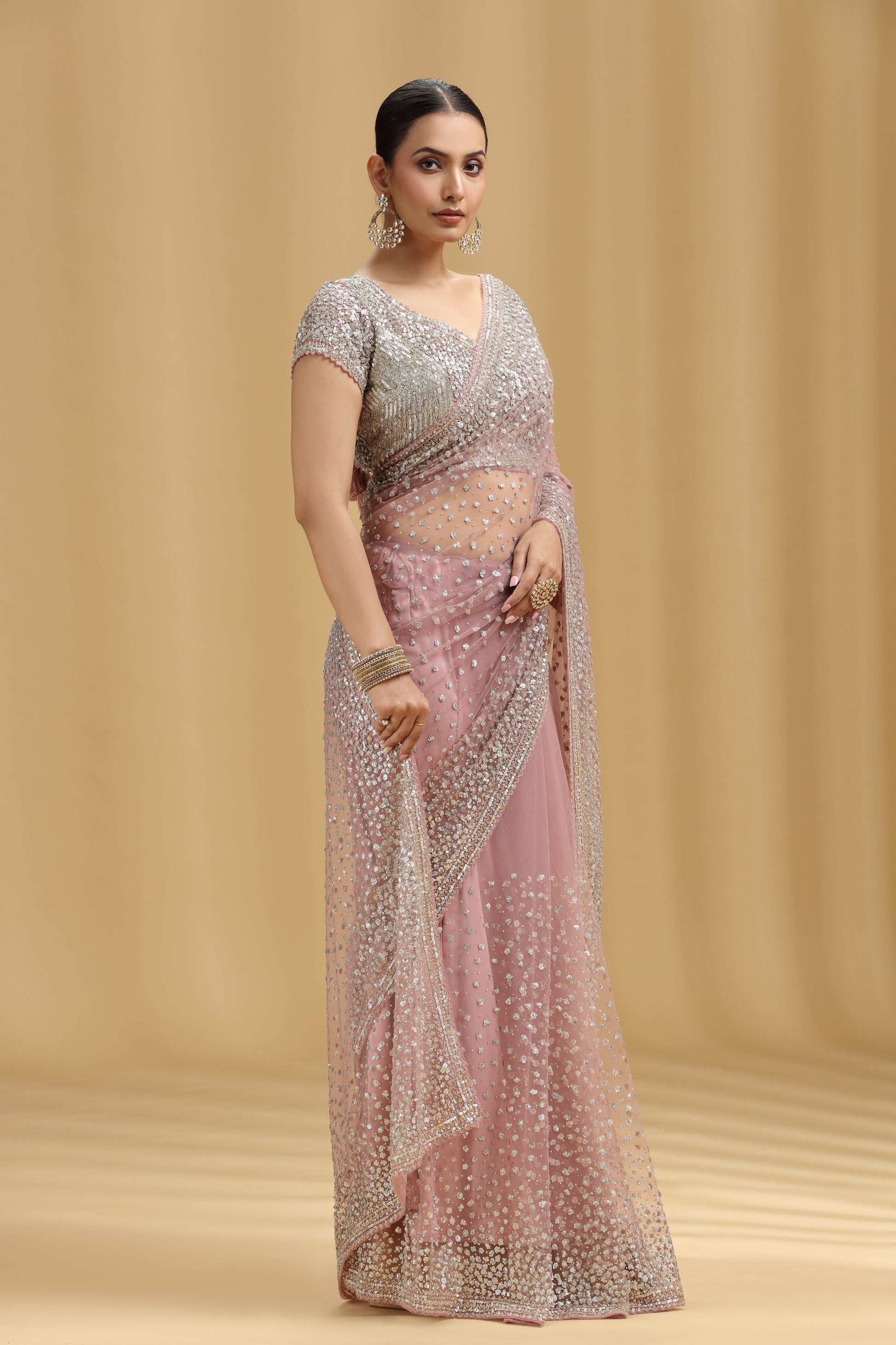 Woman wearing a silver and pink Mauve Net saree against a beige background