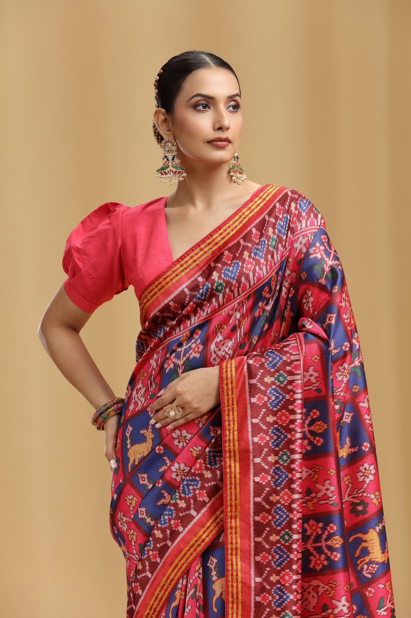 Woman wearing a vibrant saree with a red blouse against a beige background