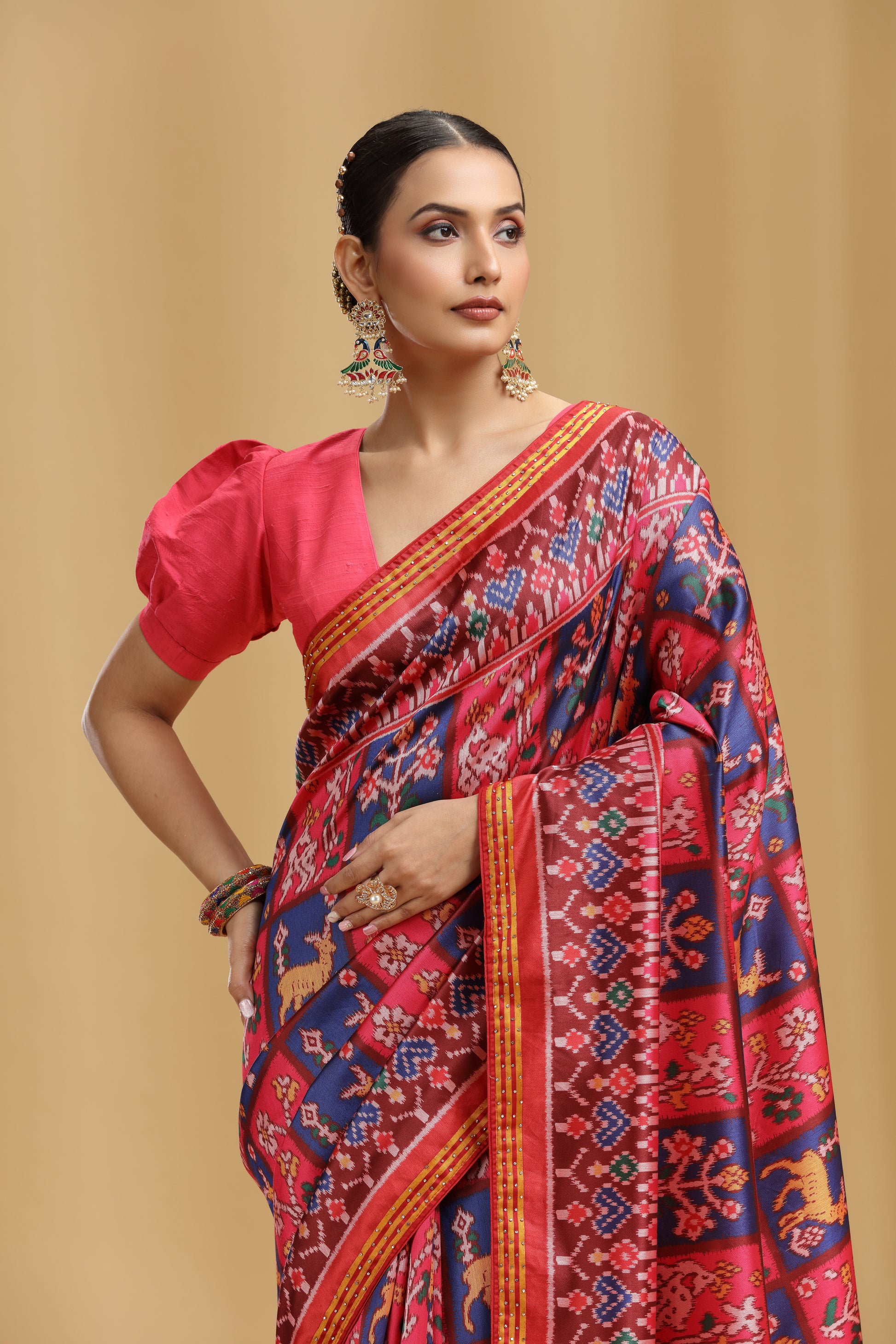 Woman wearing a vibrant saree with a red blouse against a beige background