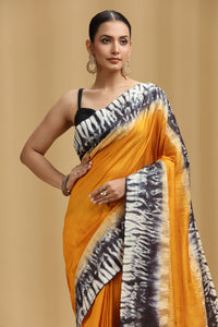 Woman wearing a yellow saree with a black and white pattern on a beige background