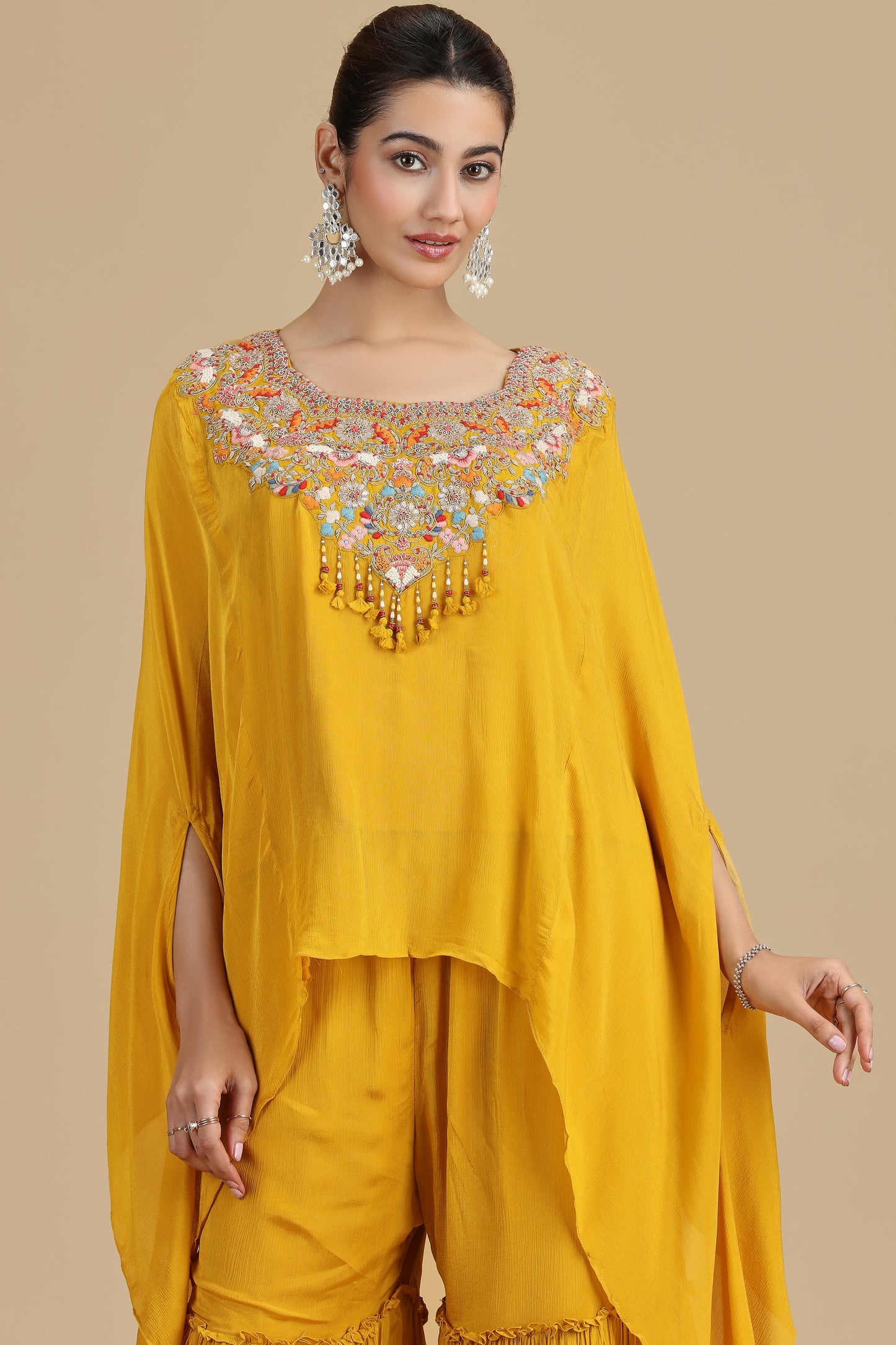Woman wearing a mustard kurta set with intricate embroidery on a beige background