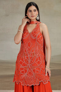 Woman wearing a red embroidered dress against a neutral background